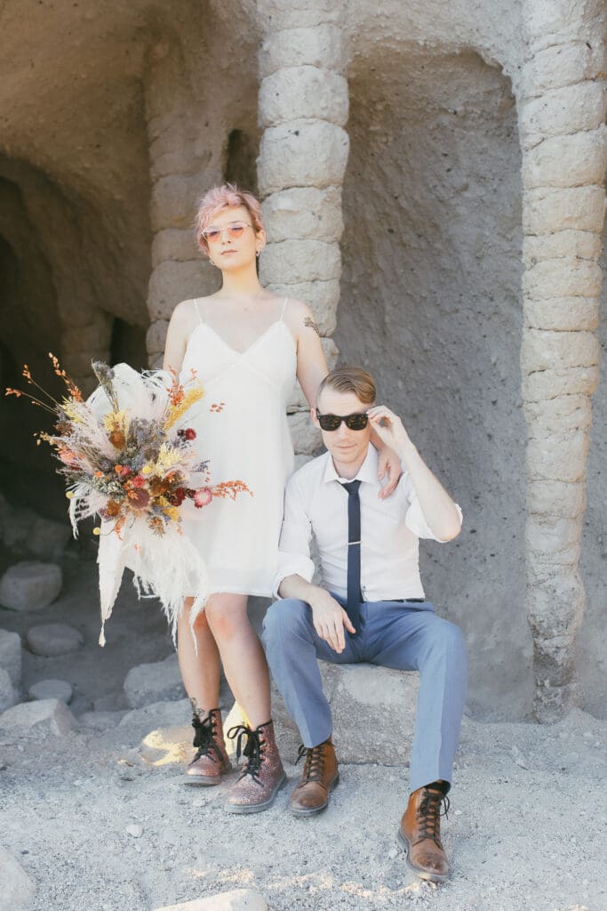 A bride and a groom pose in front of the strange columns at Crowley lake on their wedding day. 