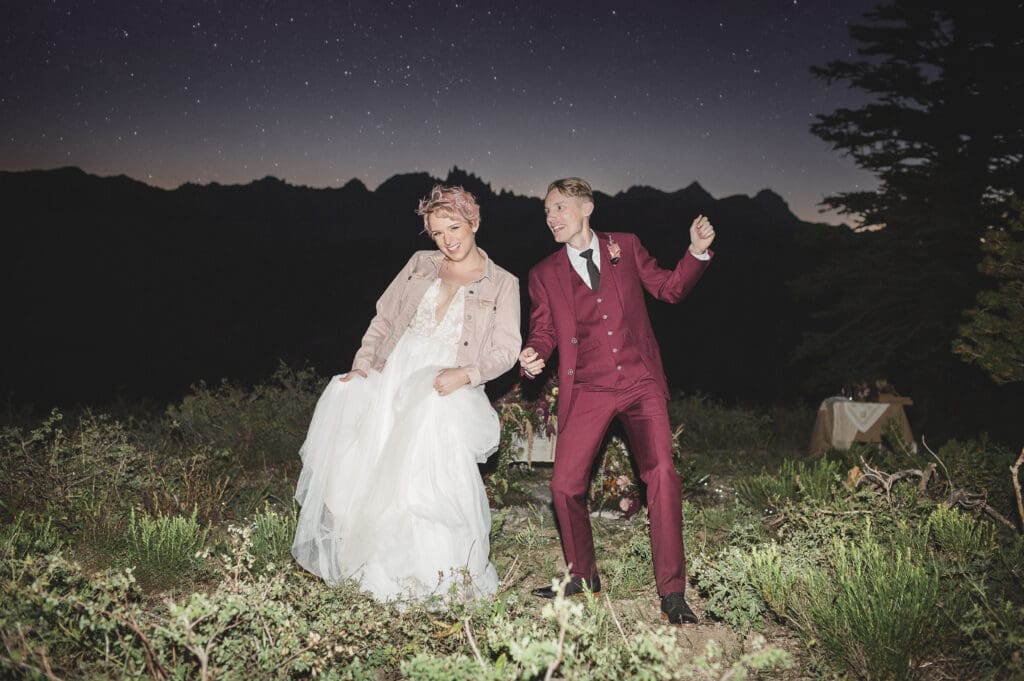 A bride and groom dance together at night, while the stars come out over the darkened mountain tops. 
