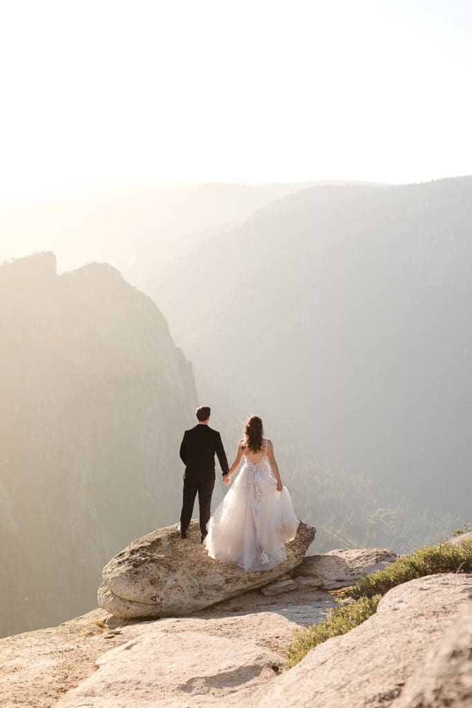 A bride and groom look into Yosemite valley from a bird's eye view at Taft Point.