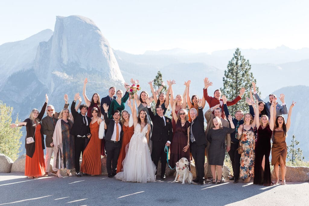 A bride and groom surrounded by all their guests in front of Half Dome in Yosemite National Park.
