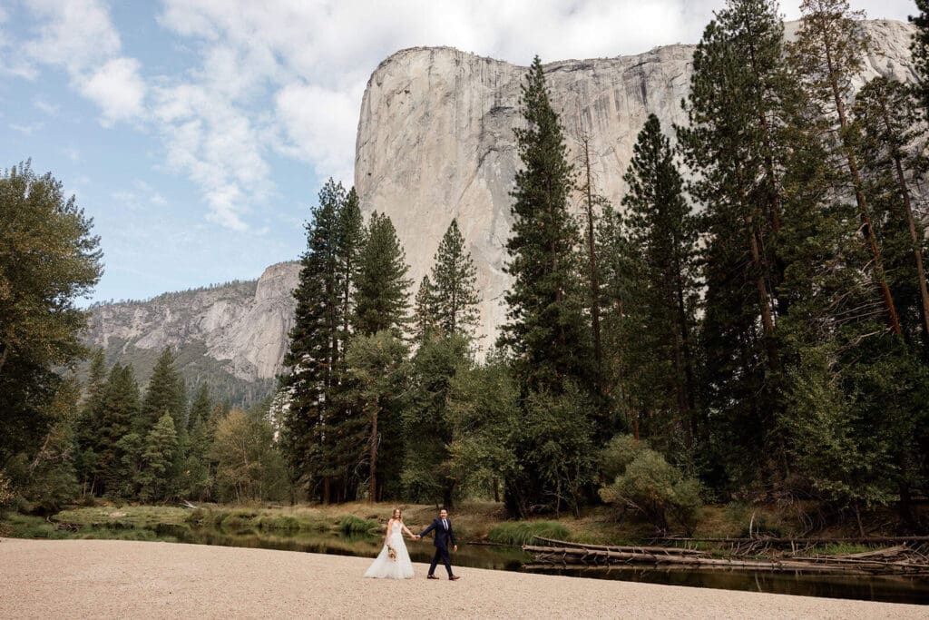 A bride and groom take a walk on Cathedral Beach in Yosemite.