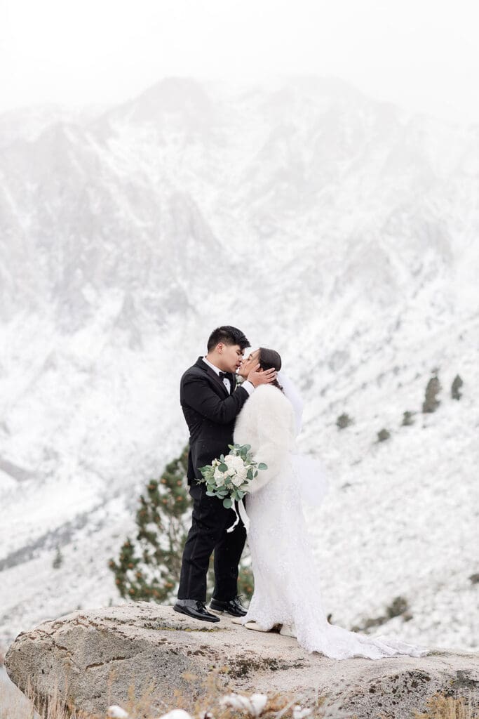 A bride and groom kiss on a snowy wedding day in Mammoth Lakes