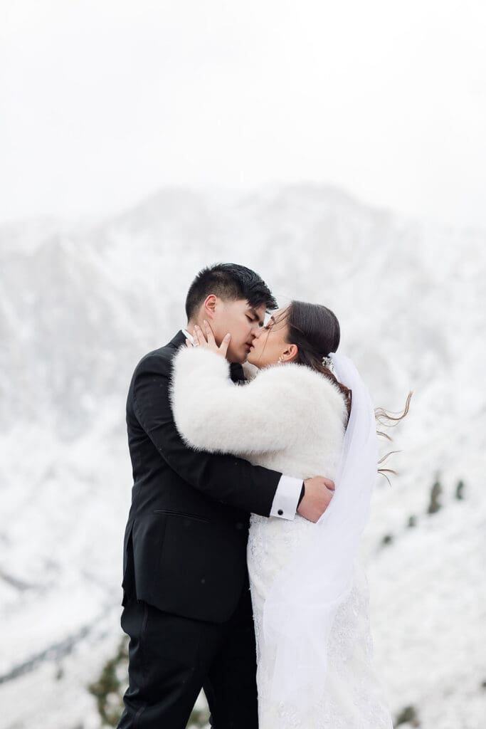 A bride and groom kiss on a snowy wedding day in Mammoth Lakes