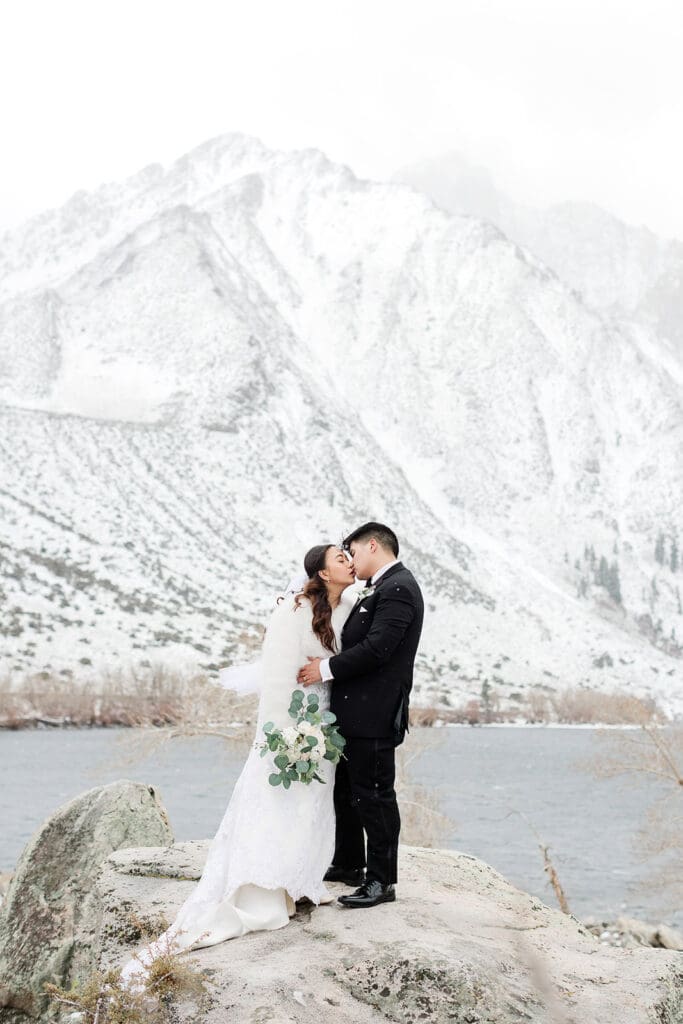 A bride and groom kiss on a snowy wedding day at Convict Lake in Mammoth Lakes.