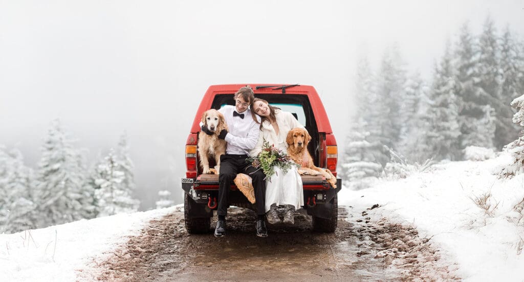 A bride and groom sit on the tailgate of their truck on their Mammoth Lakes wedding in the snow.