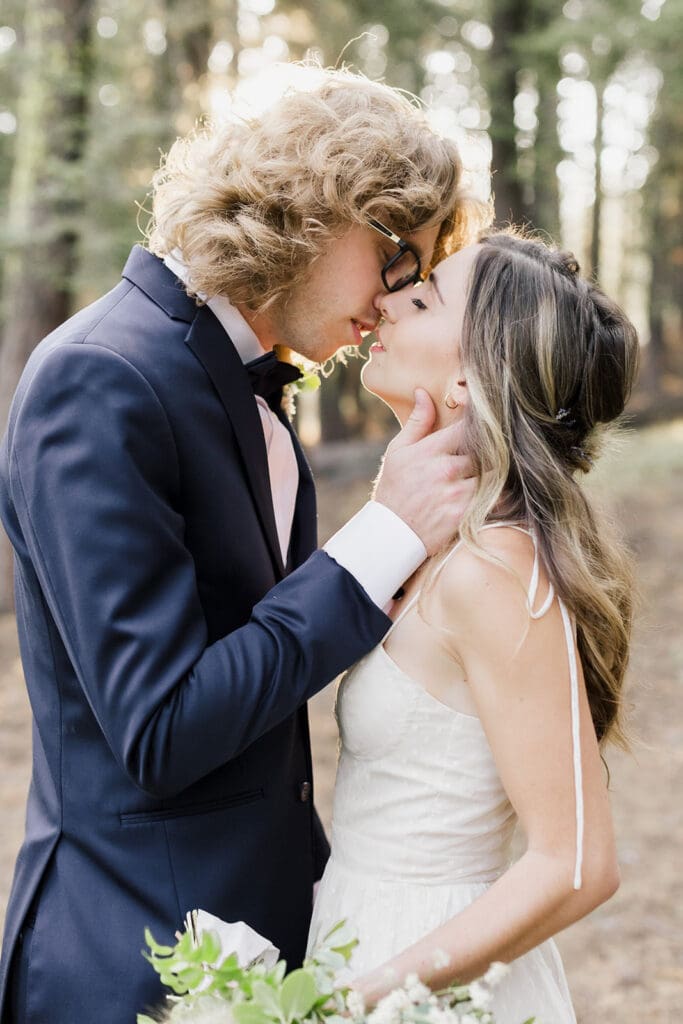 A bride and groom kiss in a forest on their wedding day in Mammoth Lakes.