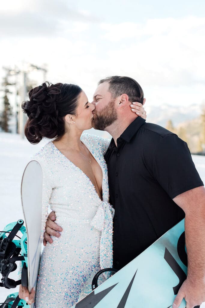 Snowboarding bride and groom kiss on their wedding day.