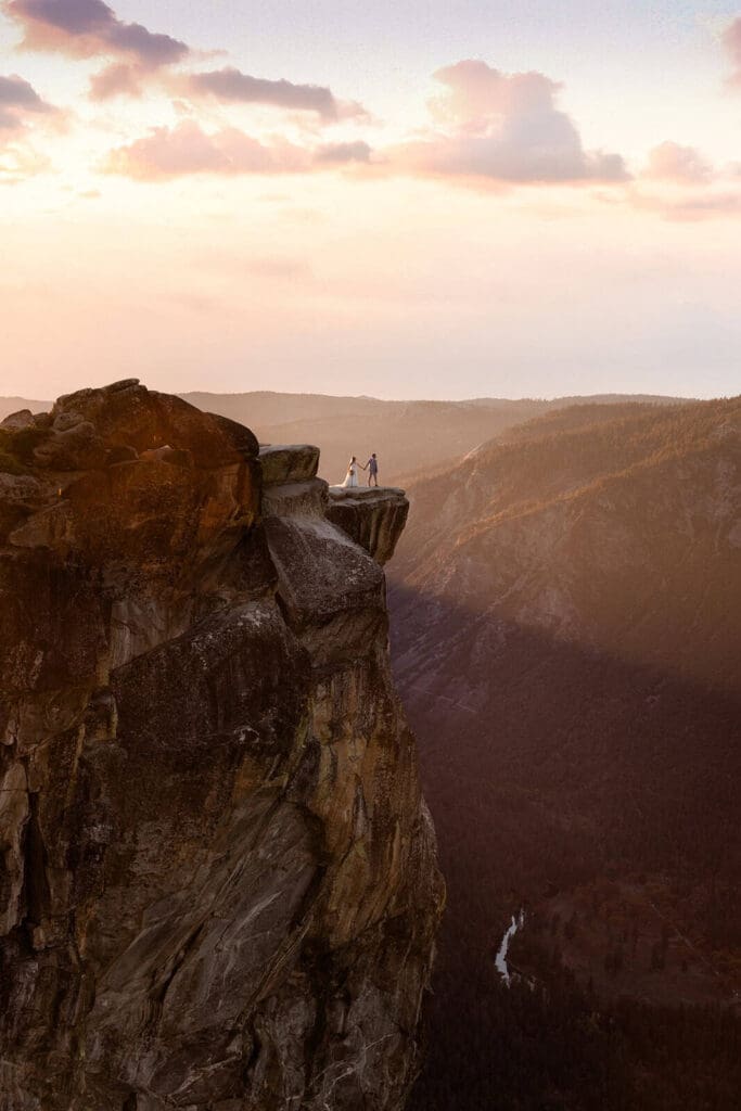 A bride and groom stand at Taft Point during a beautiful sunset.