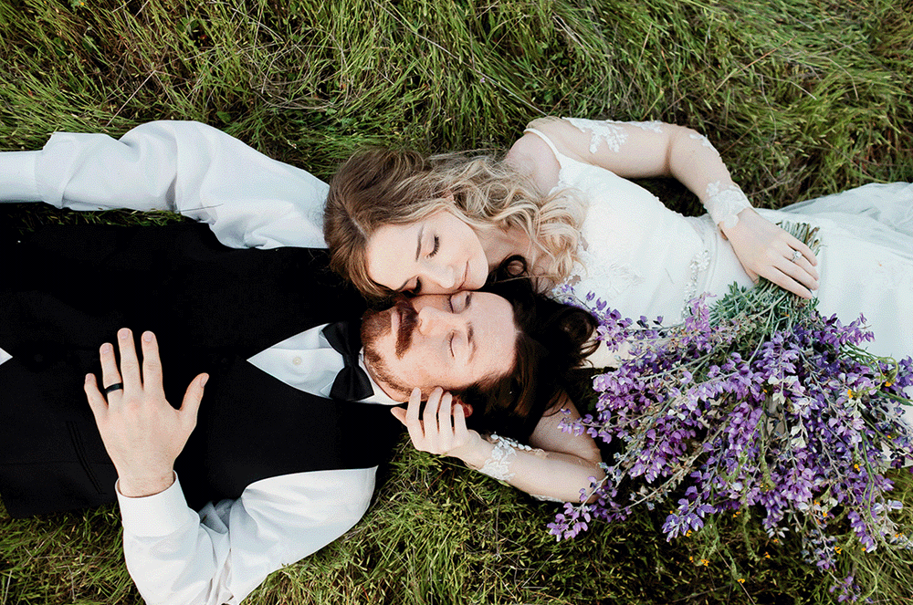 A couple lays in a lush green meadow